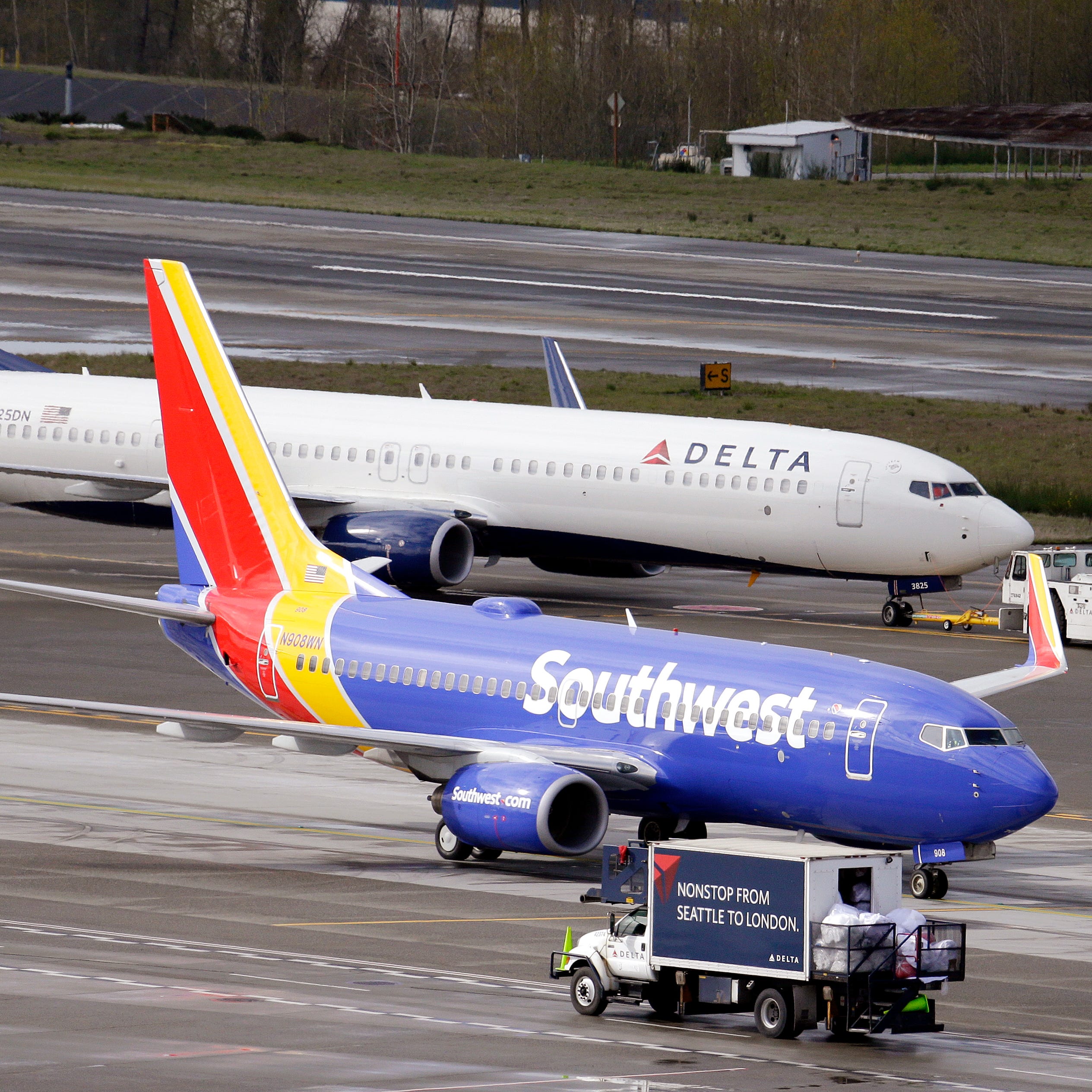 In this photo taken Tuesday, March 24, 2015, a Delta jet is pulled past a Southwest plane at Seattle-Tacoma International Airport in SeaTac, Wash. (AP Photo/Elaine Thompson)