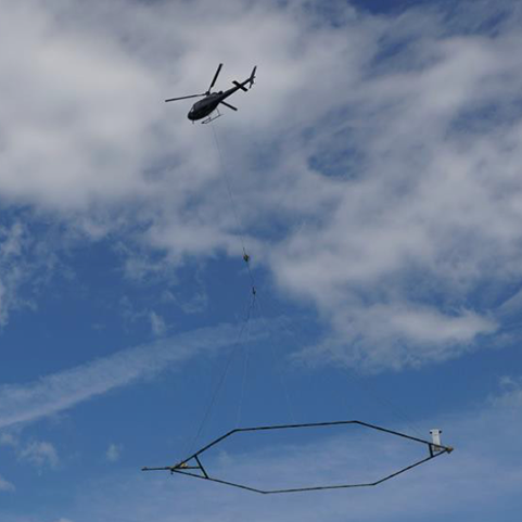 A low-flying helicopter towing a geophysical device collects scientific data for salinity and aquifer mapping.