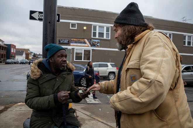 Jimmy Doom, 57, actor, writer, bartender, and former lead singer of a punk rock band, gives money to his friend Anthony who's currently experiencing homelessness in Hamtramck on Jan. 19, 2023. Jimmy has formed a friendship with Anthony over time and says he tries to help whenever he can.