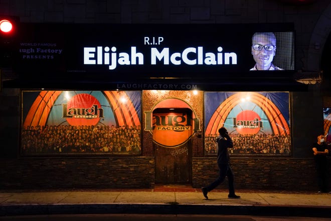 Seorang pria berjalan melewati pajangan yang menunjukkan gambar Elijah McClain di luar Laugh Factory selama nyala lilin untuk McClain di Los Angeles pada 24 Agustus 2020.