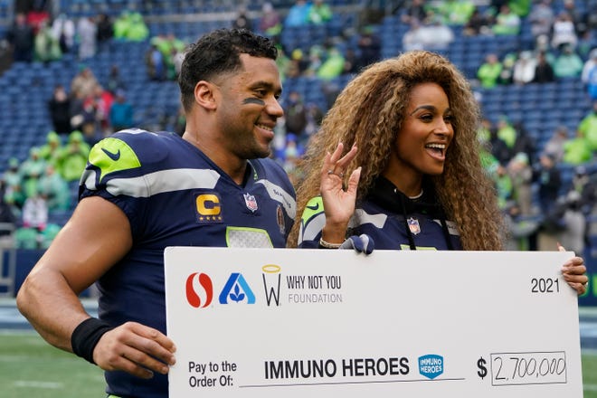 Seattle Seahawks quarterback Russell Wilson and wife Ciara pose for a photo with a charitable donation check during a ceremony before a game against the Detroit Lions at Lumen Field in Seattle on Jan. 2, 2022.