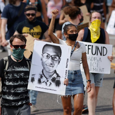 FILE - Demonstrators carry placards as they walk down Sable Boulevard during a rally and march over the death of Elijah McClain in Aurora, Colo., on June 27, 2020. A group of police officers and paramedics charged in the death of McClain, a 23-year-old Black man who was forcibly restrained and injected with a powerful sedative, are scheduled to appear in court Friday, Jan. 20, 2023, to enter pleas to the allegations.  (AP Photo/David Zalubowski, File)