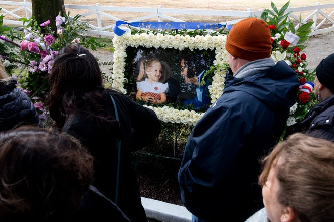 Mourners look at a flower arrangement with a picture of Lisa Marie and Elvis Presley within it while waiting in the procession to pass through the Meditation Garden after the celebration of life for Lisa Marie Presley at Graceland in Memphis, Tenn., on Sunday, January 22, 2023. 