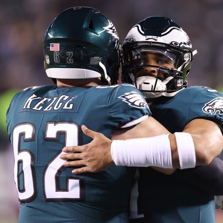 Philadelphia Eagles center Jason Kelce (62) and quarterback Jalen Hurts (1) embrace before the game against the New York Giants.