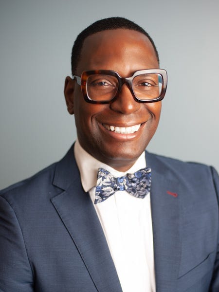 Khalid Mumin, wearing glasses and a bow tie.