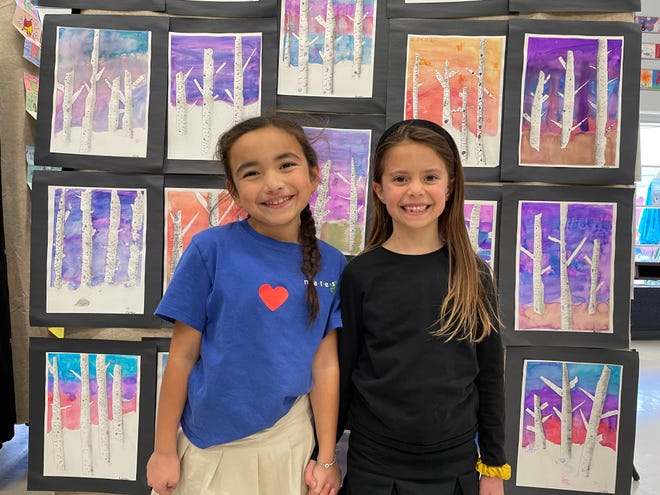 Adaline Herrera and Samantha Glazer, first-graders at Meadows Arts and Technology Elementary School in Thousand Oaks, pose with student artwork prepared for the school's winter art gallery.