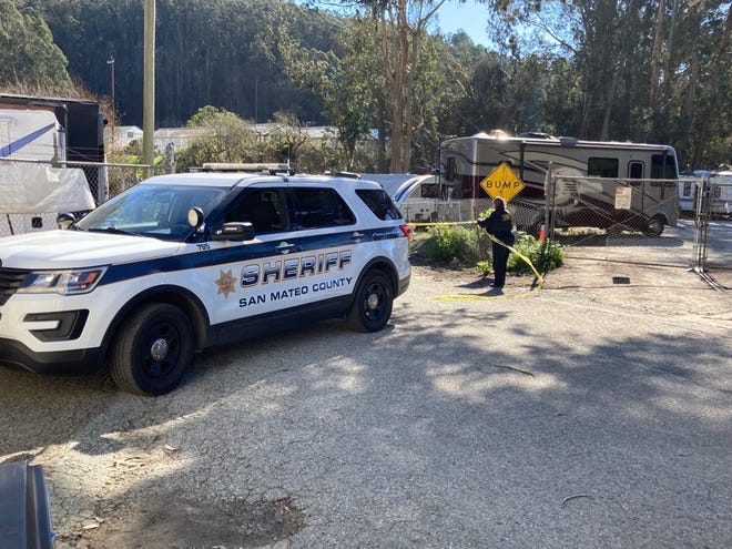 L'adjoint du shérif du comté de San Mateo est photographié mardi en train d'installer du ruban jaune à l'extérieur de la ferme de champignons de montagne à Half Moon Bay, en Californie.