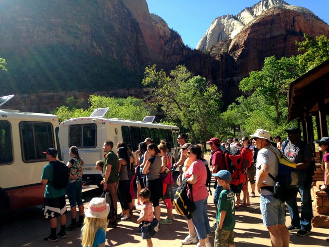 Crowds wait in line to board a shuttle bus beneath the red cliffs of Zion National Park. Preliminary counts at the park showed more than 4.6 million people visited the park in 2022.
