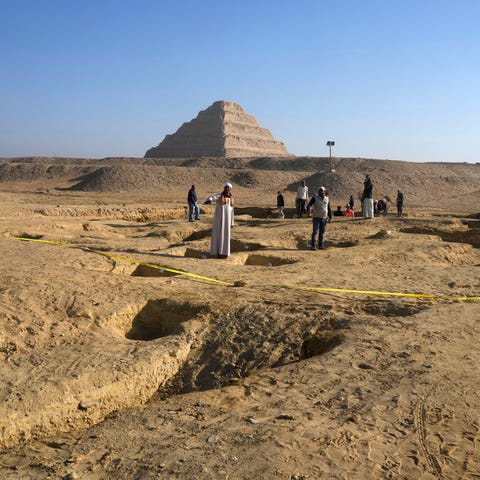 Egyptian antiquities workers dig at the site of th
