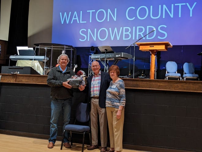 Len and Jan Hoover present a gift basket to Mike Carman (left) in Texas. He was his 600th Snowbird to join the club.