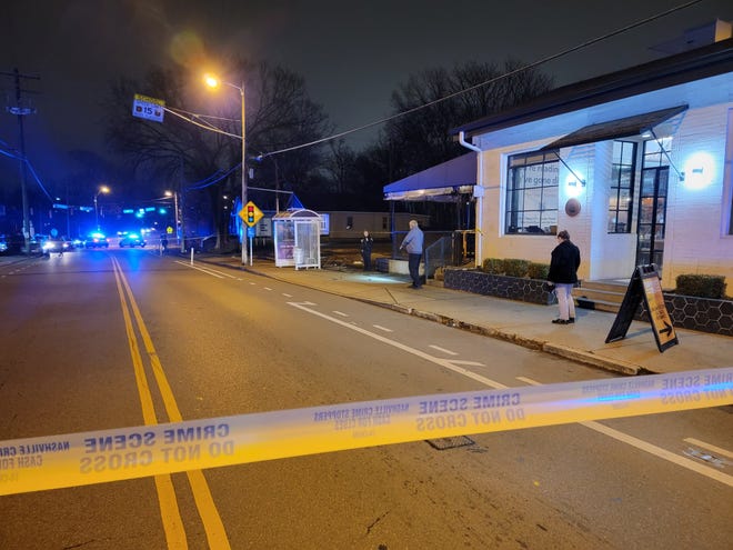 Bystanders look on as Nashville police cars line Buchanan Street after an officer fatally shot a man Sunday night.