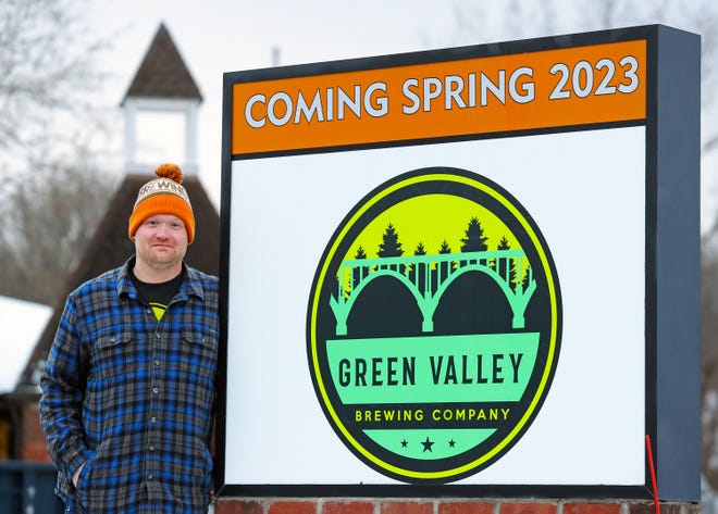 John McGroarty stands next to the sign outside of the building that will soon be the home of Green Valley Brewing Co. in Hudson.
