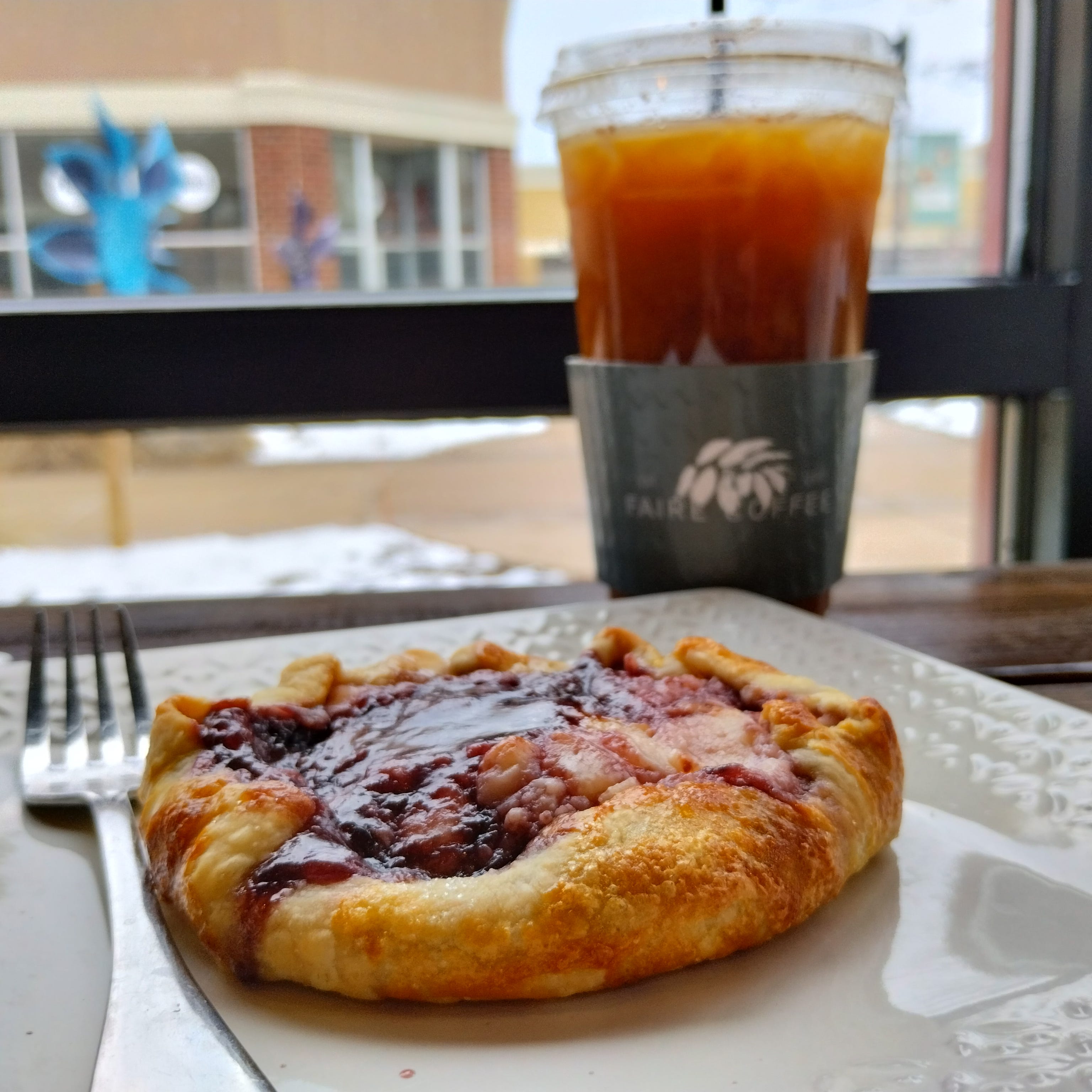 A blackberry cream cheese Galette is pictured next to a cold brew at Faire Coffee. The cafe's Peoria location is in the Shoppes at Grand Prairie.