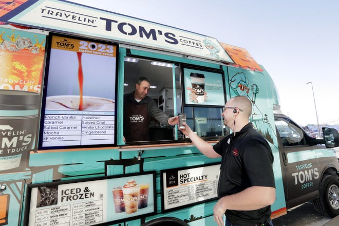 Travelin' Toms Coffee owner Jon Dietzen serves a beverage to Brent Mallmann during free hot cocoa day Tuesday at WG&R Furniture in Appleton.