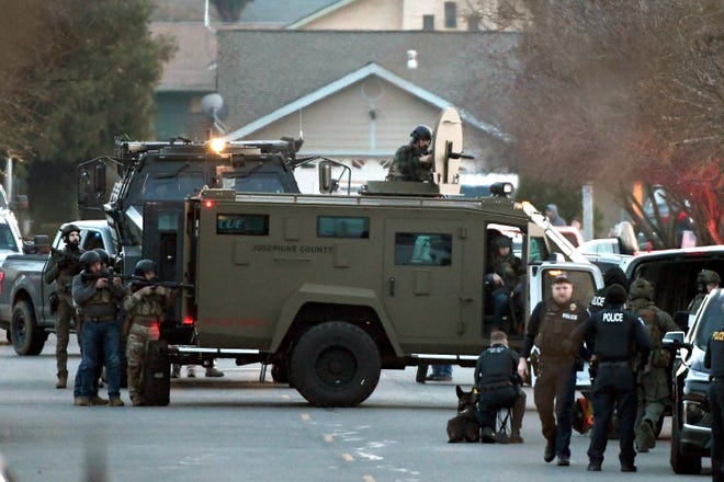 Law enforcement officers aim their weapons at a home during a standoff in Grants Pass, Oregon. Police said the standoff involving a man suspected in a violent kidnapping in Oregon who was barricaded underneath the home has been "resolved."