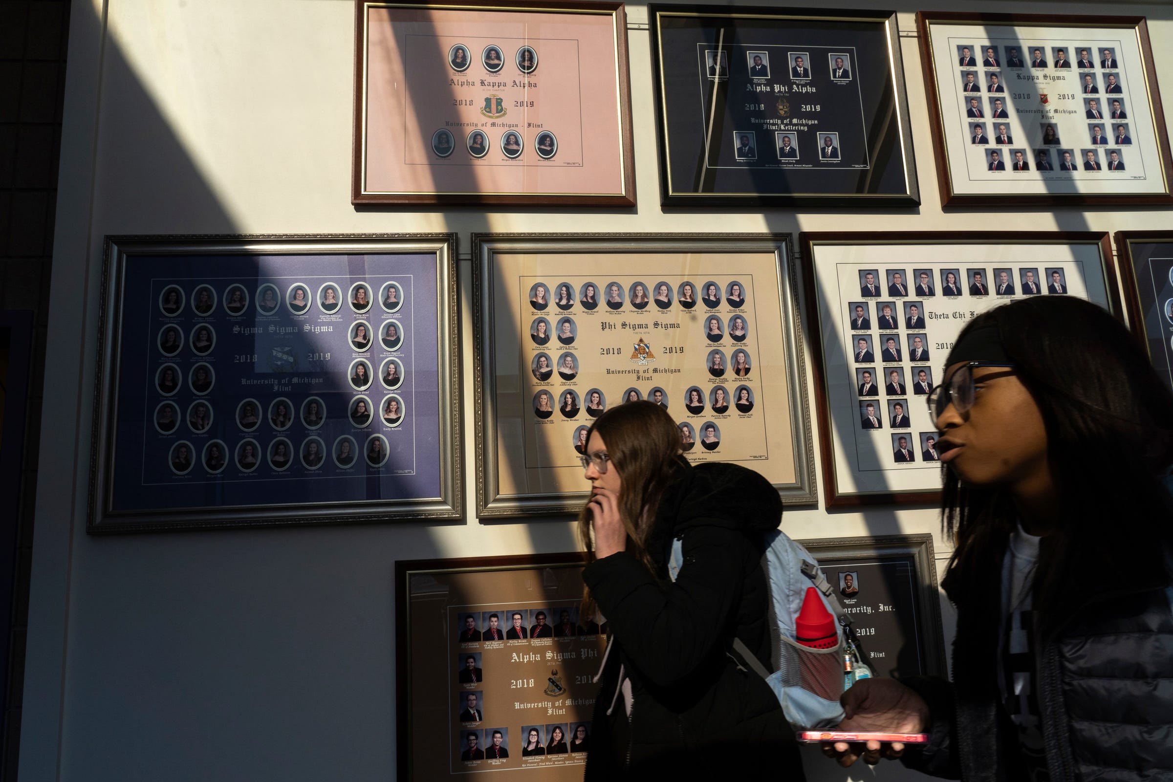 U-M Flint students walk past photos of fraternity and sorority members posted in the Harding Mott University Center at the U-M Flint campus in downtown Flint on Wednesday, Feb. 1, 2023.