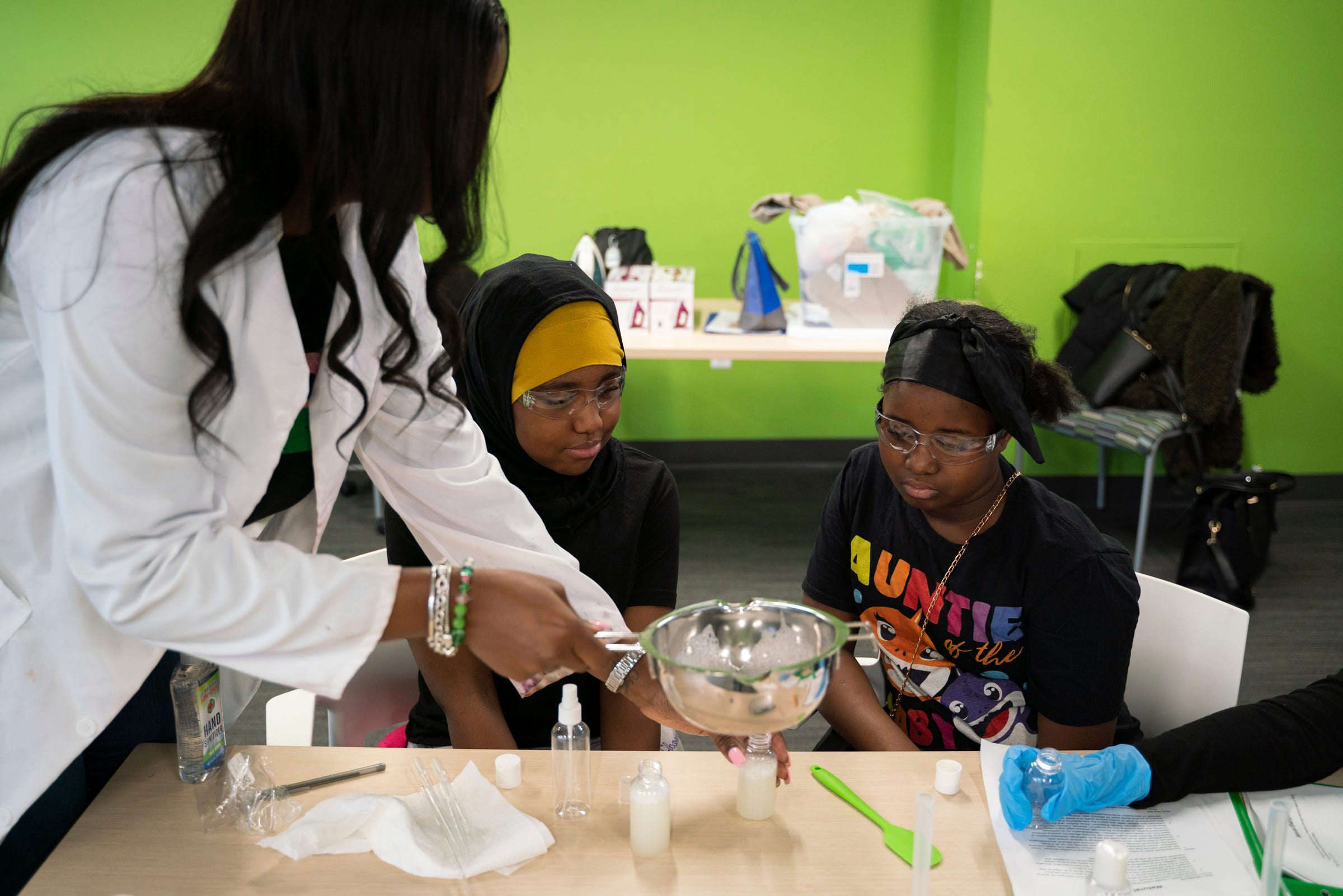 Alyssa Space, 29, lead chemist and founder of MySpaceLaboratories, left, talks with Girl Scouts Kashya Baldwin, 12, and Maleeya Hinton, 11, while helping them pour the shampoo they made into a bottle at the Ford Resource and Engagement Center in Detroit, Saturday, Jan. 28, 2023.