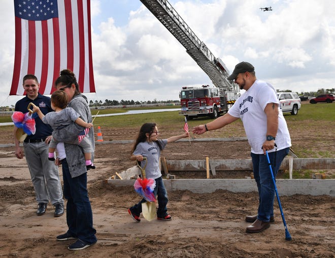 U.S. Army veteran Lucio Gaytan holds a small American flag for his son, Lucious, 5, while his wife, Ivette holds their daughter, Lyanna, 1, prior to a ground-breaking ceremony on Friday, for the mortgage-free home being built for them in the Sapphire Point neighborhood in Lakewood Ranch.