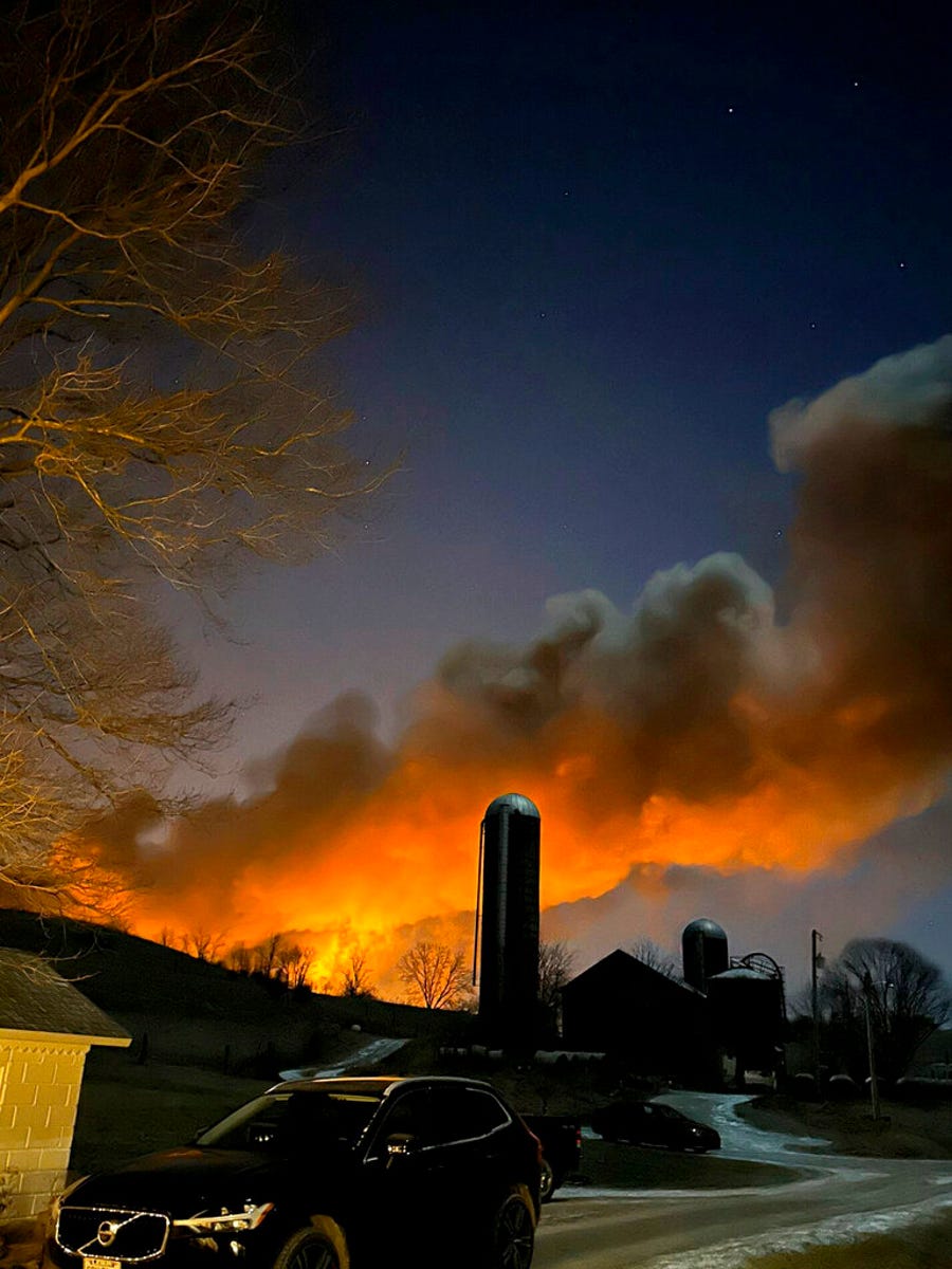 In this photo provided by Melissa Smith, a train fire is seen from her farm in East Palestine, Ohio, Friday, Feb. 3, 2023. A train derailment and resulting large fire prompted an evacuation order in the Ohio village near the Pennsylvania state line on Friday night, covering the area in billows of smoke lit orange by the flames below.