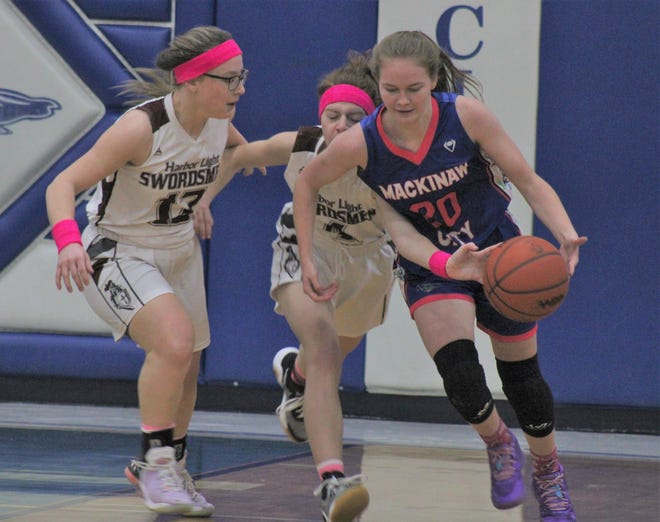 Mackinaw City junior guard Gracie Beauchamp (20) attempts to get past Harbor Light's Sarah Smith (13) and Charlotte Gagnon (4) during the first half of Monday's girls basketball contest in Mackinaw City.