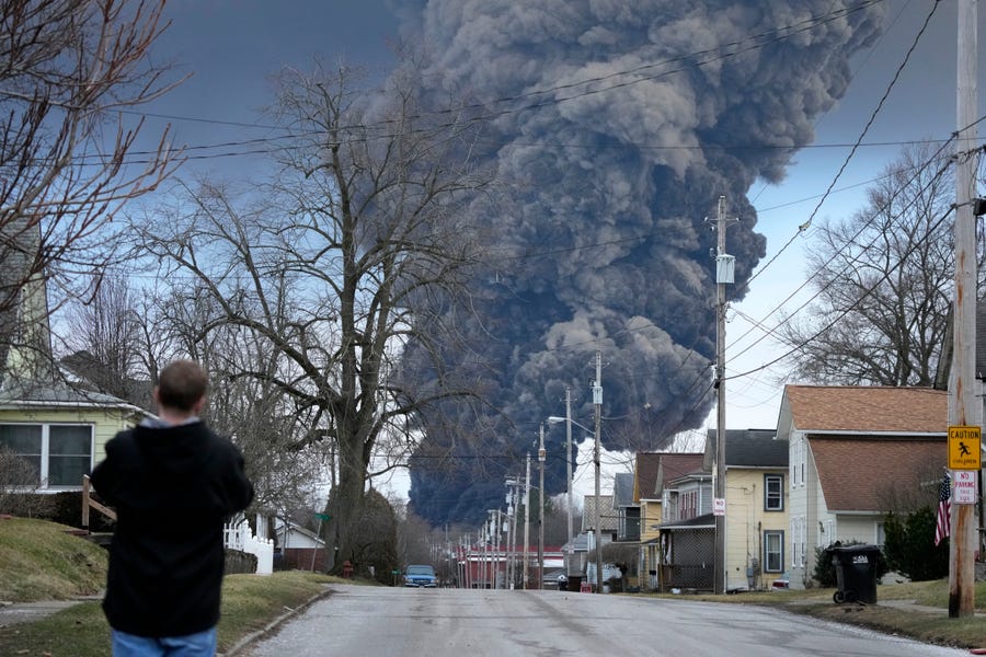 A man takes photos as a black plume rises over East Palestine, Ohio, as a result of a controlled detonation of a portion of the derailed Norfolk and Southern trains on Monday