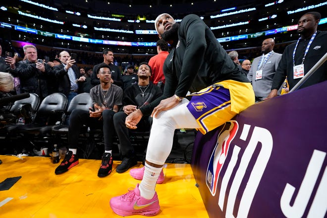Los Angeles Lakers forward LeBron James talks with his kids prior to the second half of an NBA basketball game against the Oklahoma City Thunder Tuesday, Feb. 7, 2023, in Los Angeles. (AP Photo/Ashley Landis)