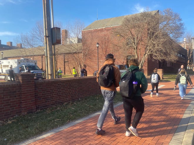 University of Delaware students walk past first responders who were called to the school for reports of a "lab safety incident."