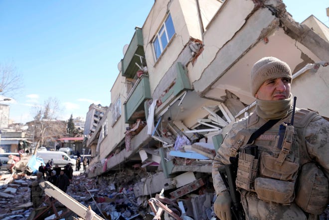 A soldier stands next to a collapsed building in Kahramanmaras, southern Turkey, Wednesday, Feb. 8, 2023. Nearly two days after the magnitude 7.8 quake struck southeastern Turkey and northern Syria, thinly stretched rescue teams work to pull more people from the rubble of thousands of buildings.
