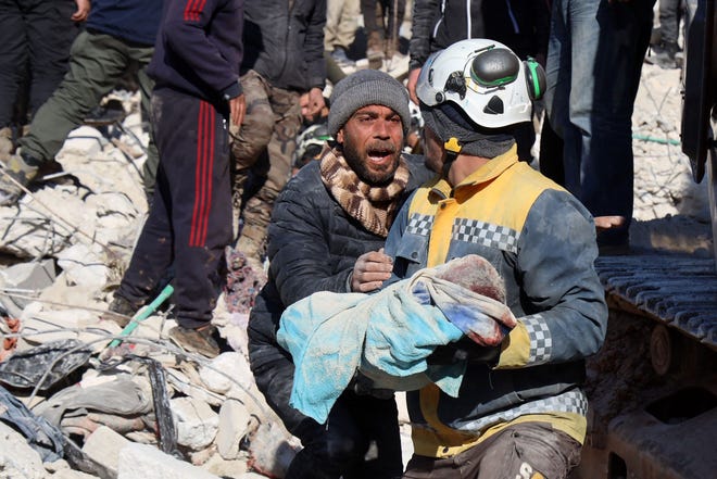 The father of a baby whose body is pulled out from the rubble by a Syrian White Helmet rescue worker reacts.