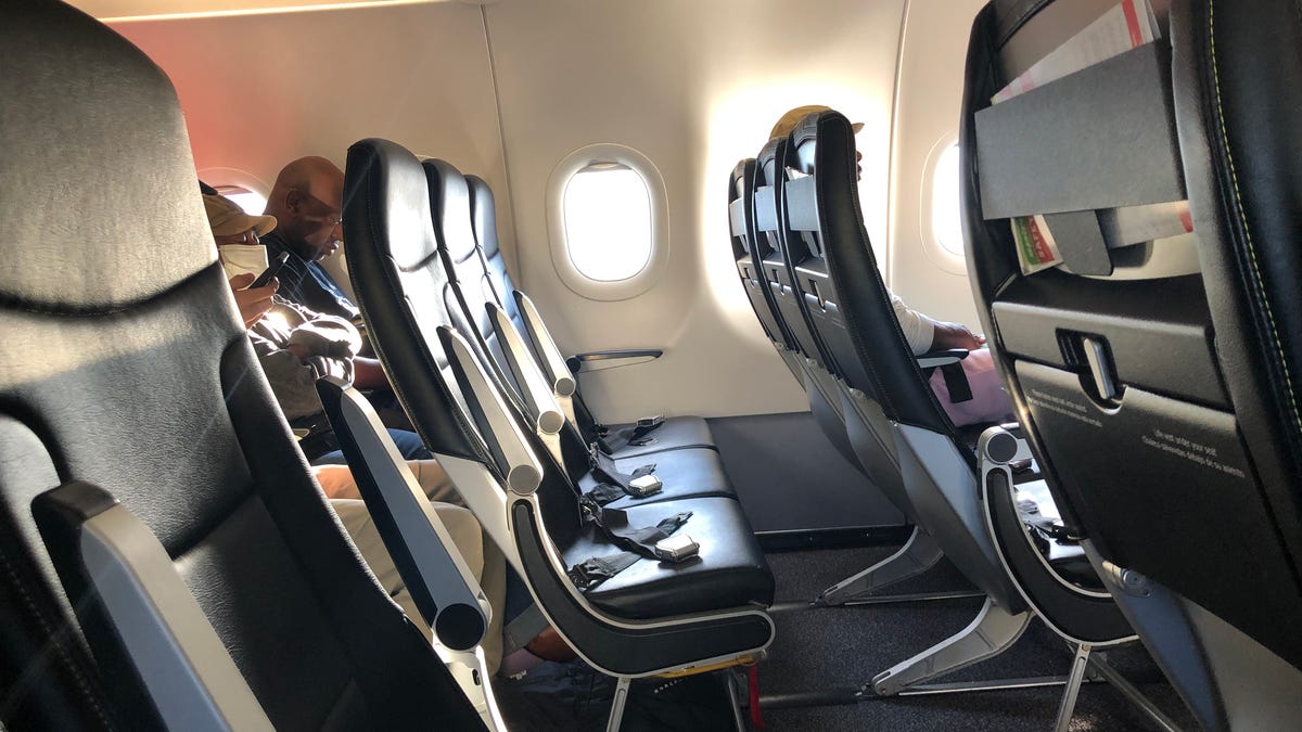 An empty row of seats with seatbelts visible on a Spirit Airlines flight.