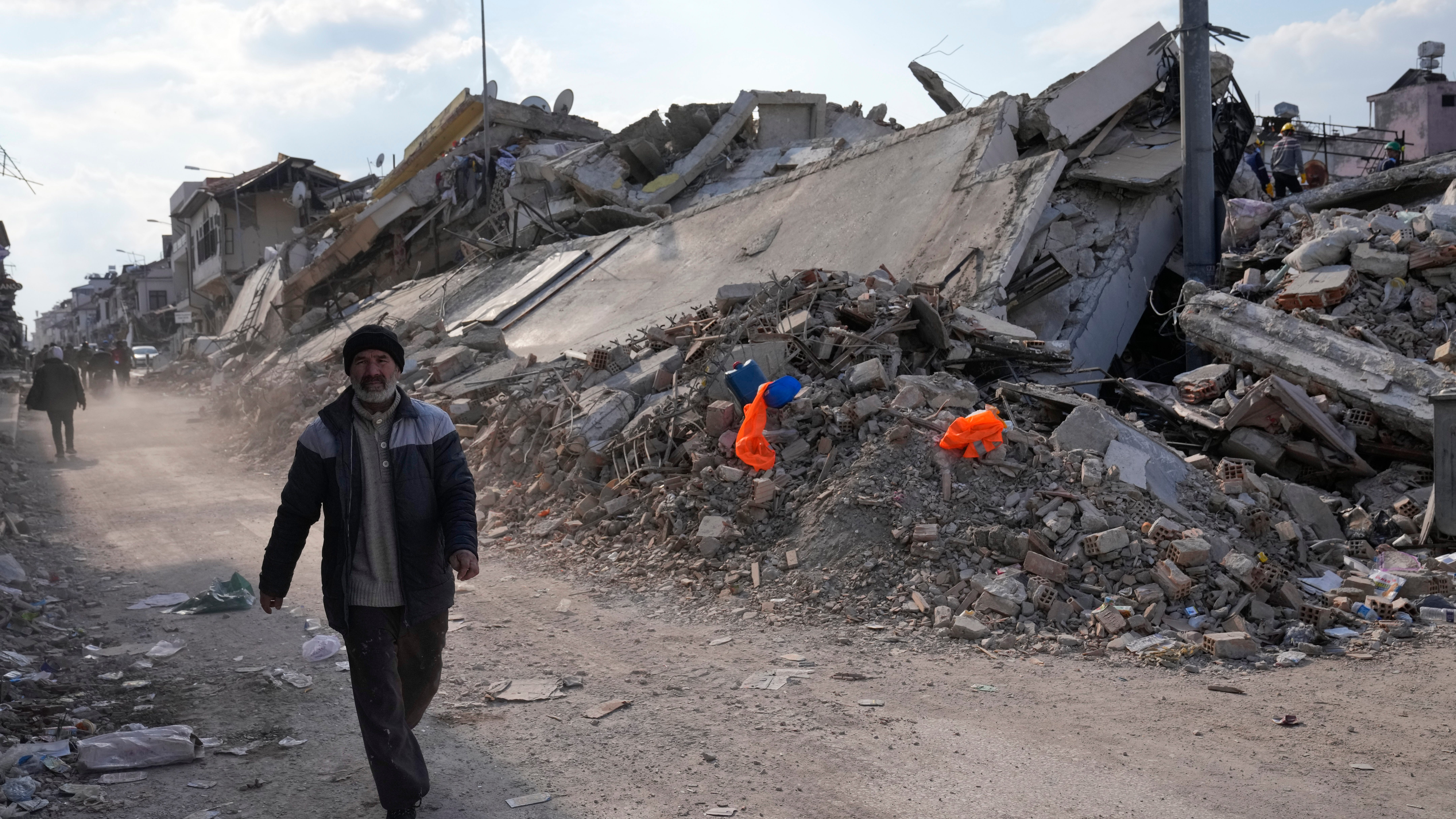 A man passes collapsed buildings in Antakya, Turkey, Saturday, Feb. 11, 2023. Emergency crews made a series of dramatic rescues in Turkey on Friday and Saturday, pulling several people from the rubble days after a catastrophic 7.8-magnitude earthquake killed thousands in Turkey and Syria.