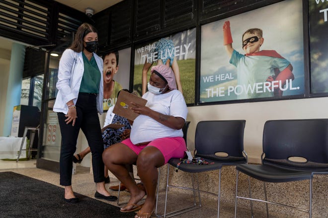     Stephanie Trujillo Rodriguez helps Jackie Edwards, who is expecting twins, register for her first vaccination with Pfizer's COVID-19 vaccine "Game date for vaccination" at the Palm Beach Children's Hospital at St. Mary's Medical Center in West Palm Beach, in this August 31, 2021 photo.