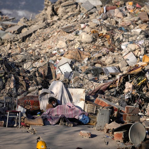 A man sleeps in front of a destroyed building in K