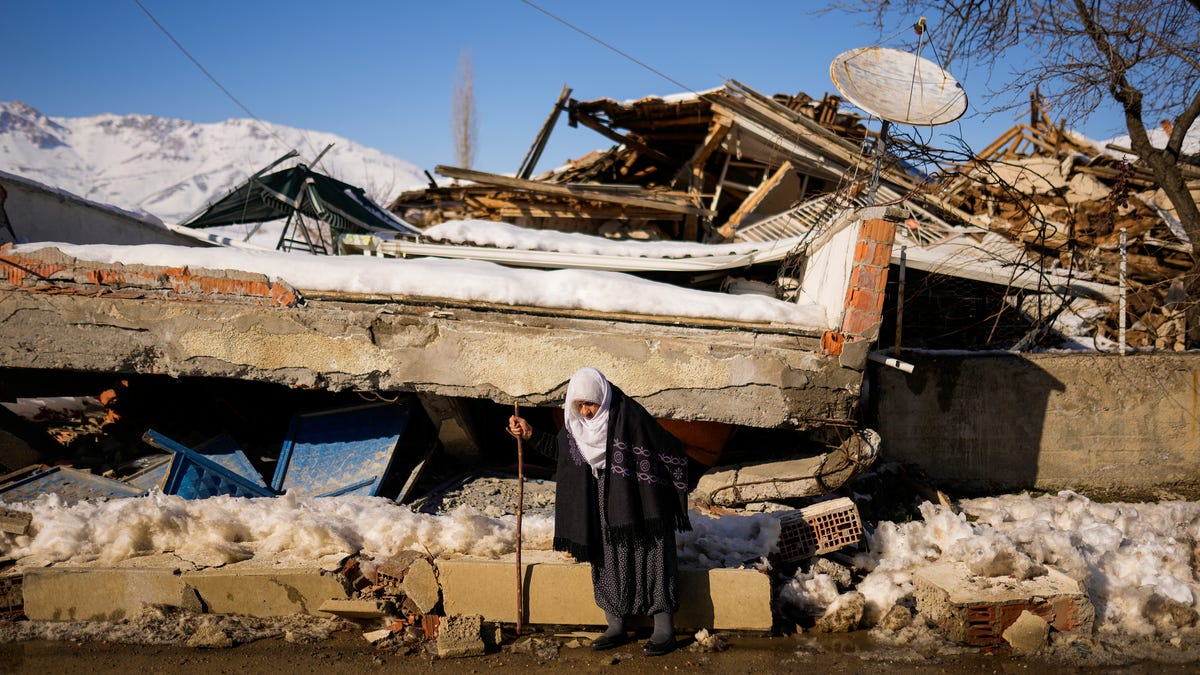 Zehra Kurukafa walks past a destroyed house in the village of Polat, Turkey, Sunday, Feb. 12, 2023