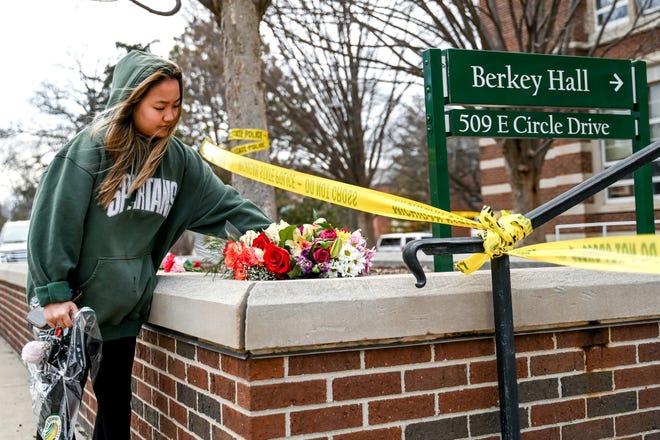 Michigan State University senior Ashley Le places flowers outside Berkey Hall on Tuesday, Feb. 14, 2023, in honor of those killed on the MSU campus in East Lansing.