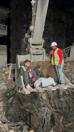 トルコのアンタキヤで発生した地震のがれきから遺体を回収し、掘削機のバケツに乗るレスキュー隊員サラム・アルディーン (左)。