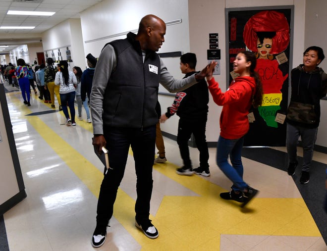 Brandon Osborne high-fives students at Stafford Elementary School as they go to class Wednesday. Osborne was a physical education teacher at the school for 13 years prior to his current position as executive director of Dodge Jones Youth Sports Center. He joined other leaders Wednesday at Stafford sharing his experiences for a Black History Month program