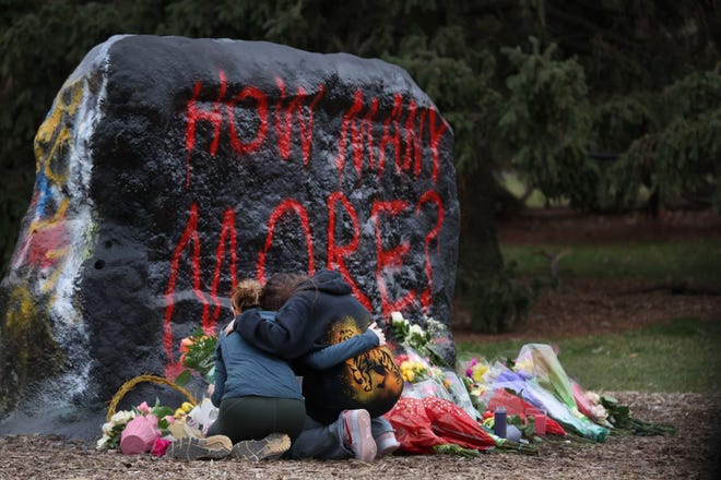 People leave flowers, mourn, pray and cry at a makeshift memorial at "The Rock" on the campus Michigan State University on Feb. 14, 2023 in Lansing, Michigan.