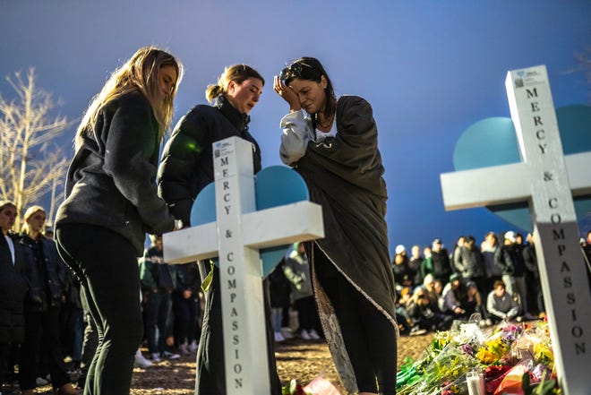 People sign a heart on a cross in memory of one of the people killed during a vigil at the Rock on the Michigan State University campus in East Lansing on Wednesday, Feb. 15, 2023, to honor and remember the victims of the mass shooting that happened on the MSU campus that left three dead and five others injured.