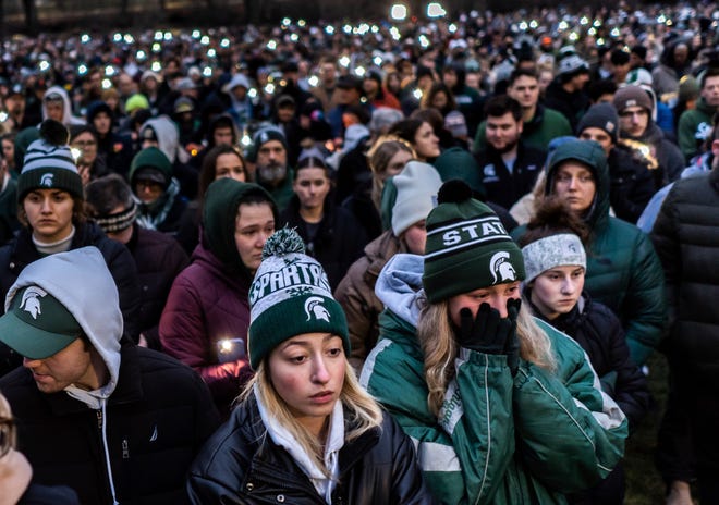 People stand together during a vigil at The Rock on the Michigan State University campus in East Lansing on Wednesday, February 15, 2023, to honor and remember the victims of the mass shooting that happened on the MSU campus that left three dead and multiple others injured.
