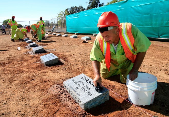 FILE - Steven Abujen, a California prison inmate with the Prison Industry Authority, cleans one of the newly installed headstones at the Mormon Island Relocation Cemetery, near Folsom, Calif., on Oct. 18, 2011. Lawmakers in Nevada and California are advancing legislation to remove involuntary servitude from their state constitutions, a move that follows four states that purged forced labor from the books in ballot measures last fall. (AP Photo/Rich Pedroncelli, File)