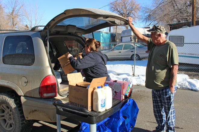Tammy King, food bank manager for FISH, a pantry in Elko, Nevada, helps a resident load food into a vehicle. King has worked at the pantry for more than 20 years.