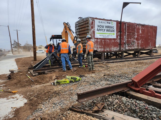 Individuals work to install a new barrier Tuesday afternoon, after a Monday morning train derailment pushed several train cars onto the roadway on Amarillo Boulevard East, blocking traffic for several hours.
