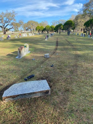 Tire tracks show the course a vehicle took through Wildwood Cemetery in Bartow on Thursday. A driver fleeing police officers lost control of his vehicle and drove through the cemetery, damaging six headstones, the Bartow Police Department said.