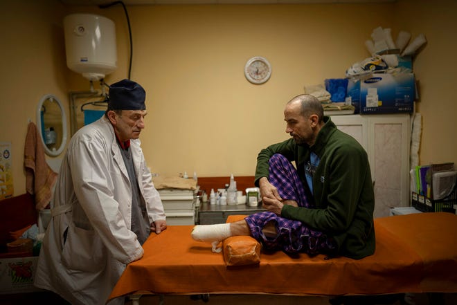 Ukrainian doctor Yury Kuznetsov speaks with landmine victim Oleksandr Korysnik at a hospital in Izium, Ukraine, on Sunday, February 18, 2023.