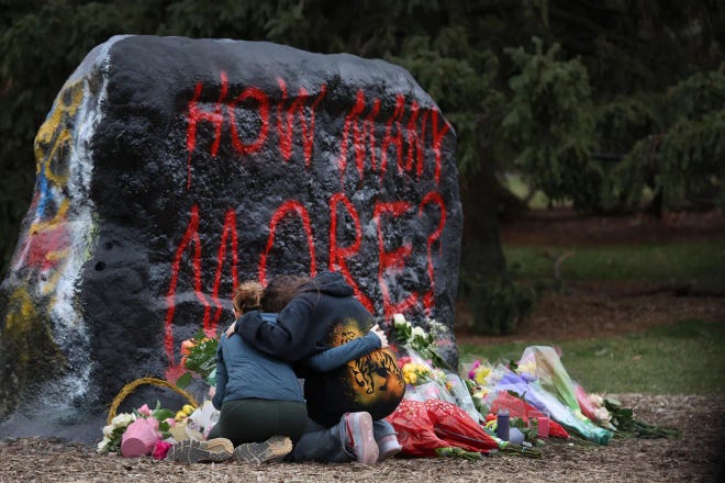 People leave flowers, mourn, pray and cry at a makeshift memorial at "The Rock" on the campus of Michigan State University on February 14, 2023 in Lansing, Michigan.