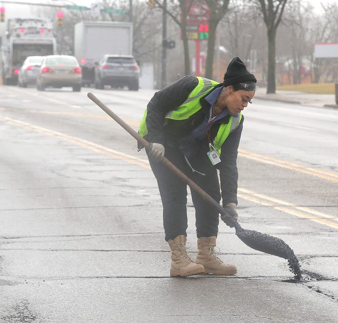 City of Akron Highway maintenance worker Shay Carter fills a pothole on East Exchange Street in Akron.