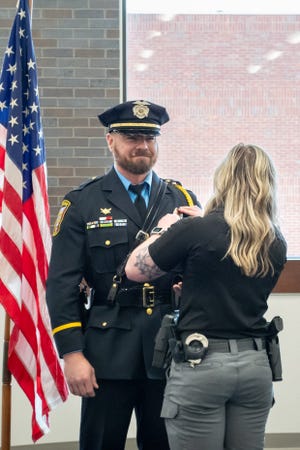 The newly sworn in Lieutenant Fred Wagner gets his badge affixed to his uniform by his wife, Jordan.