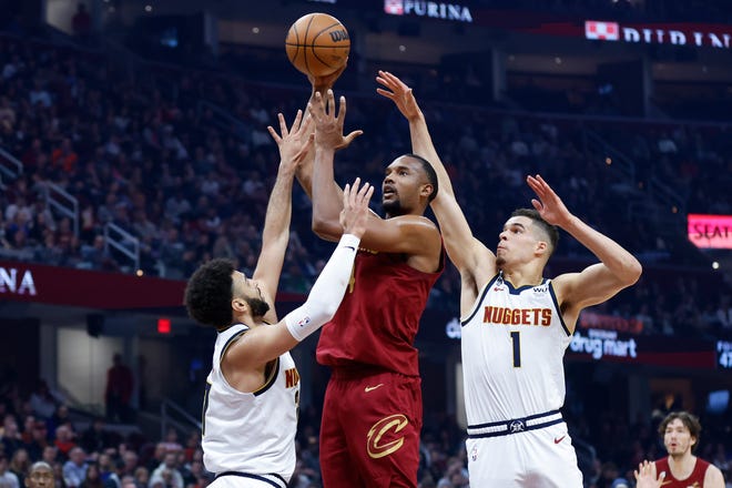 Cleveland Cavaliers forward Evan Mobley, center, shoots between Denver Nuggets guard Jamal Murray, left, and forward Michael Porter Jr. (1) during the first half of an NBA basketball game, Thursday, Feb. 23, 2023, in Cleveland. (AP Photo/Ron Schwane)