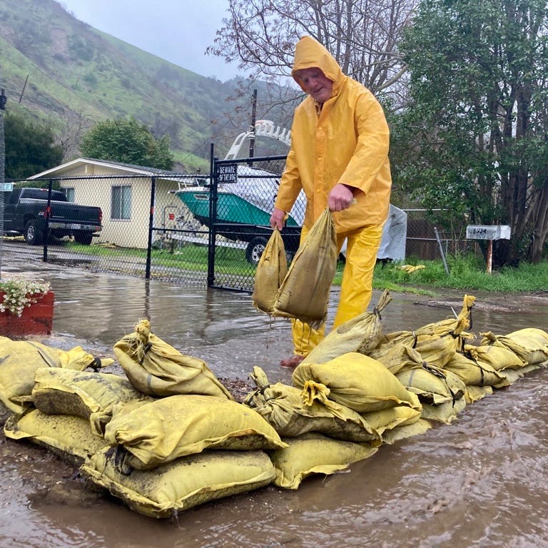 John O'Connor places sandbags out on Nye Road near Casitas Springs Friday morning, Feb. 24, 2023, as rain moves into Ventura County. O'Connor said he was moving sandbags out of the way so he could go get coffee for his daughter.